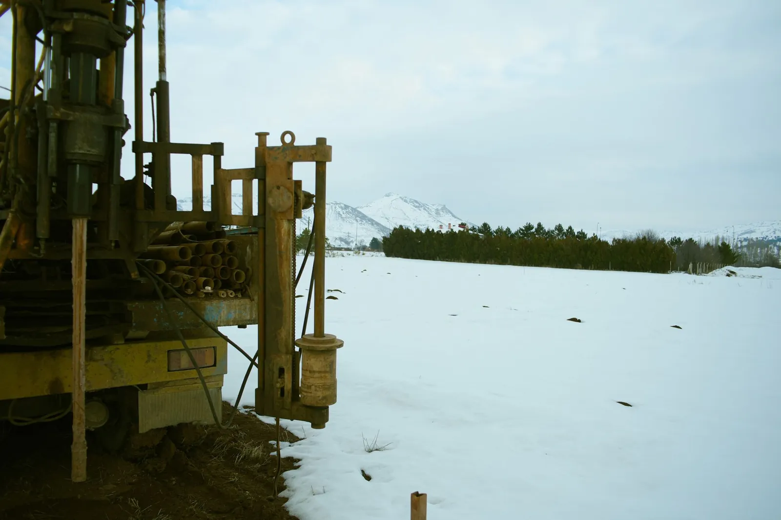 A large industrial drill machine set against a snowy winter landscape with mountains in the background. Stock photo illustrating South West Pinnacle Exploration's new order story.