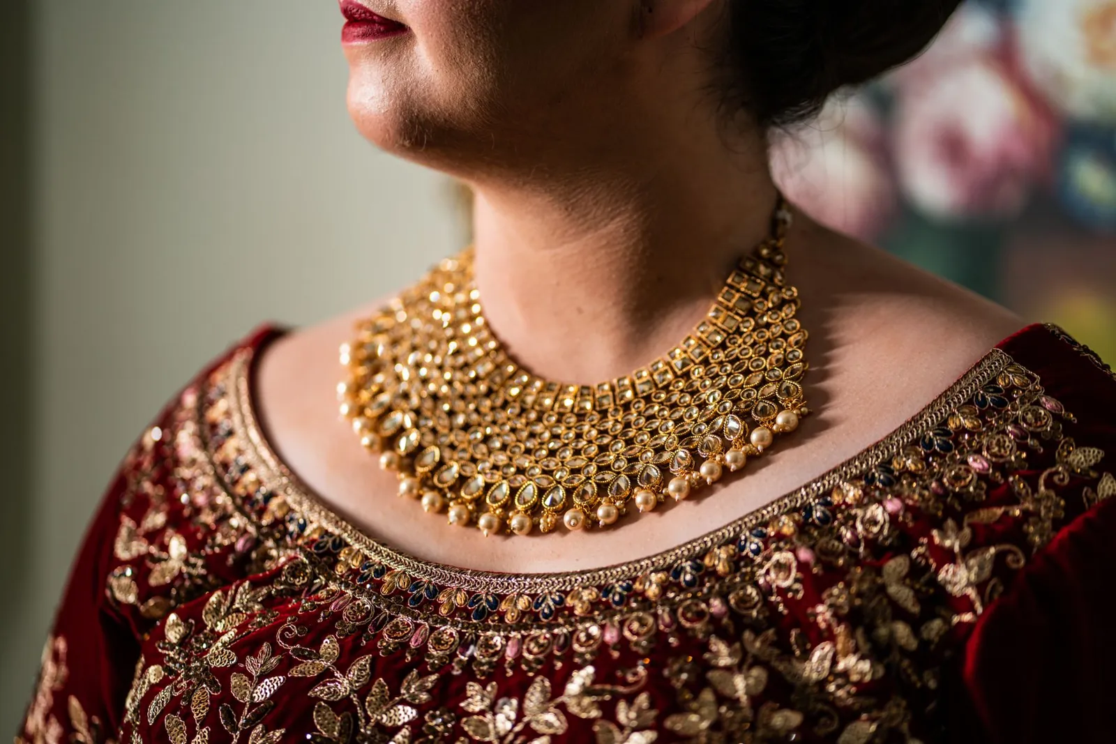 A close-up of a woman wearing a gold necklace and ornate outfit, showcasing intricate jewelry design. Stock photo illustrating Senco Gold's earning call story.