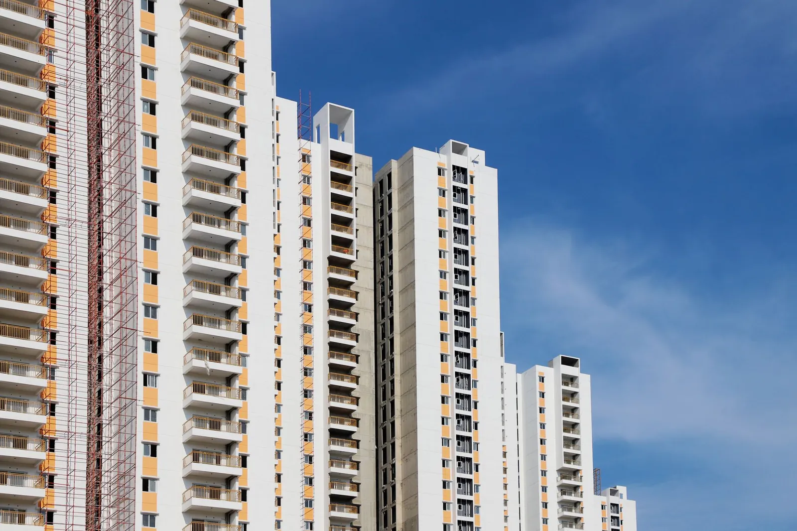 Modern high-rise residential buildings with white facades and blue sky backdrop showcasing urban architecture. Stock photo illustrating Arisinfra Solutions' new order story.