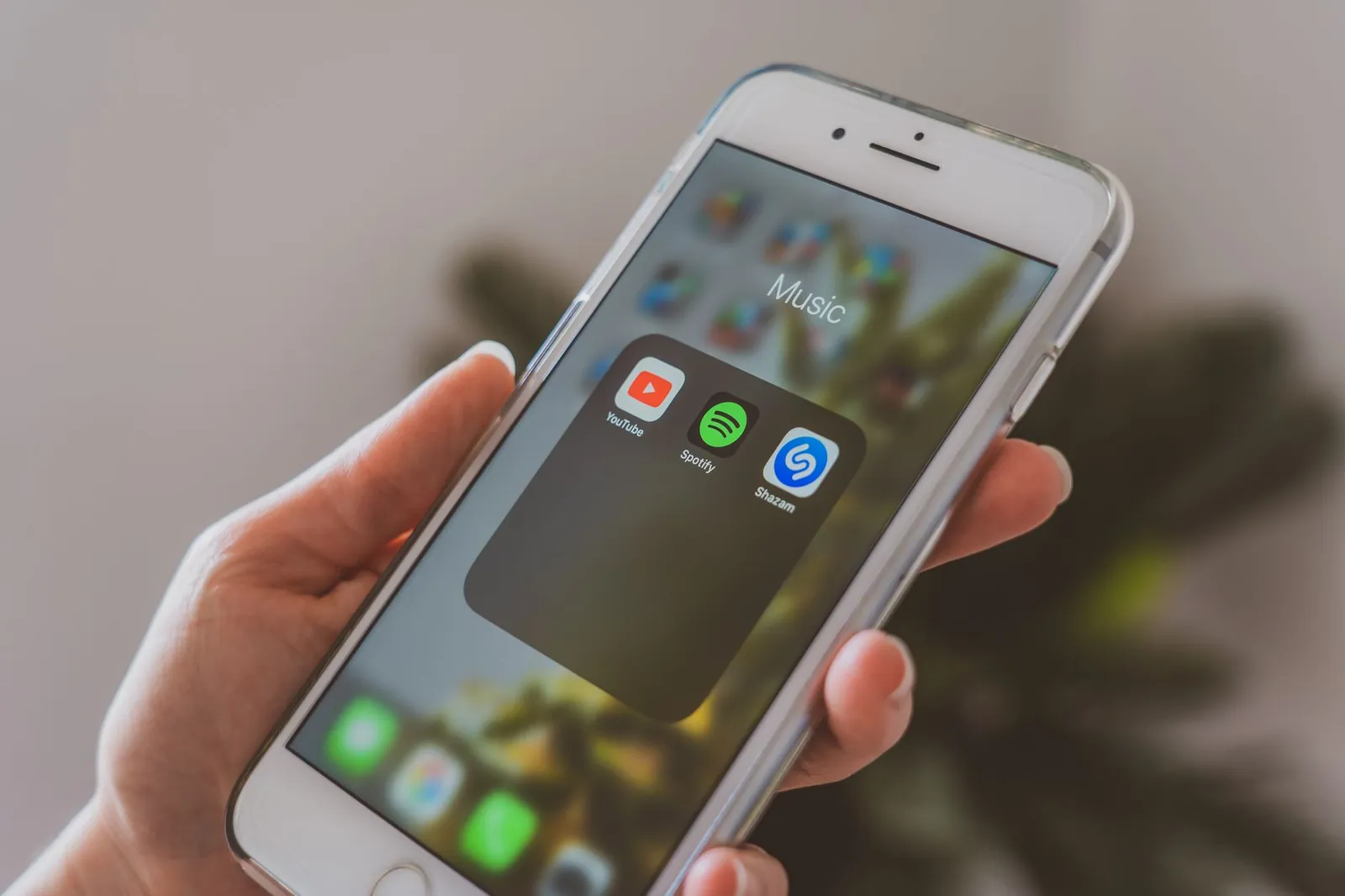 Hand holding a smartphone displaying popular music apps like Spotify and Shazam in a close-up shot. Stock photo illustrating Bharti Airtel's product launched story.