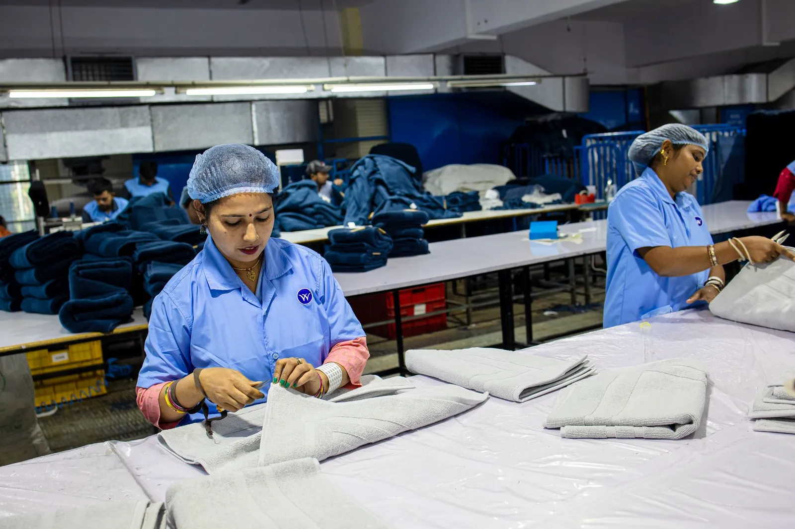Workers in a textile factory folding fabrics in an organized assembly line. Stock photo illustrating Kitex Garments' fund raise story.