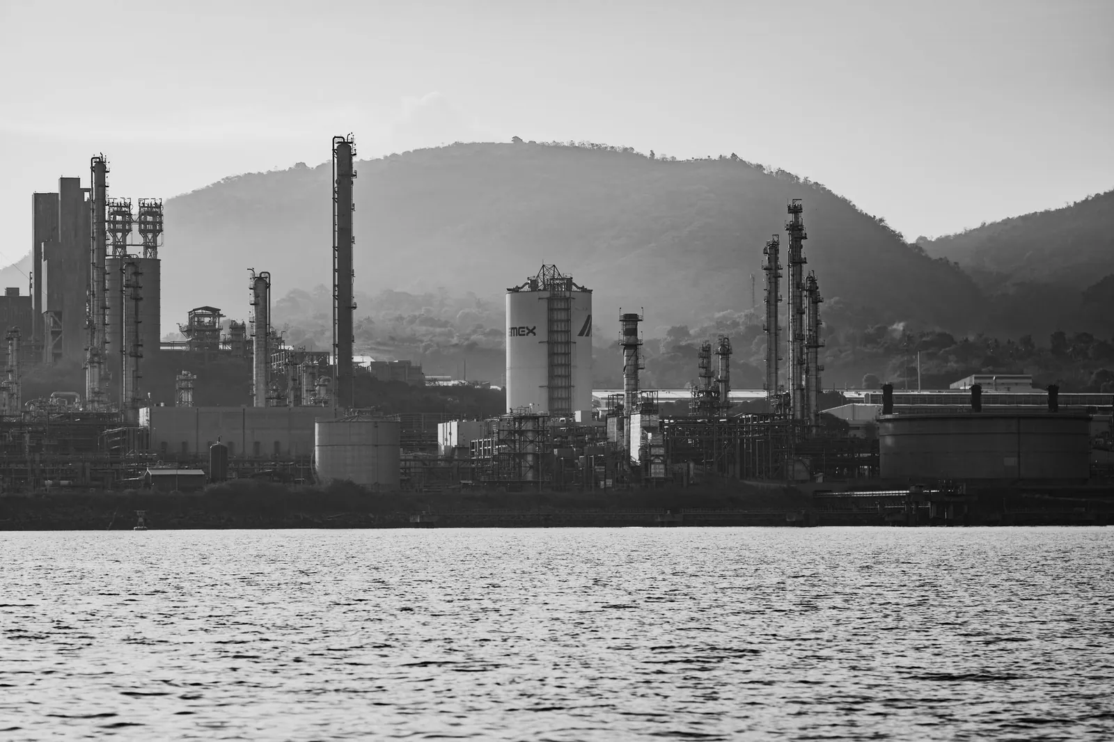 Monochrome view of an industrial complex with hills in the background, captured during the day. Stock photo illustrating TANFAC Industries' fund raise story.