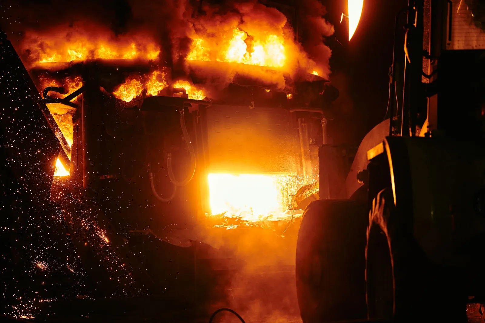 Close-up of a fiery furnace in an industrial setting emitting intense flames and sparks. Stock photo illustrating JSW Steel's financial results story.