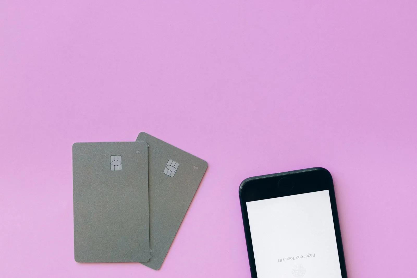 Flat lay of credit cards and smartphone on pink surface, symbolizing digital payment solutions. Stock photo illustrating Manipal Payment and Identity Solutions' financial results story.