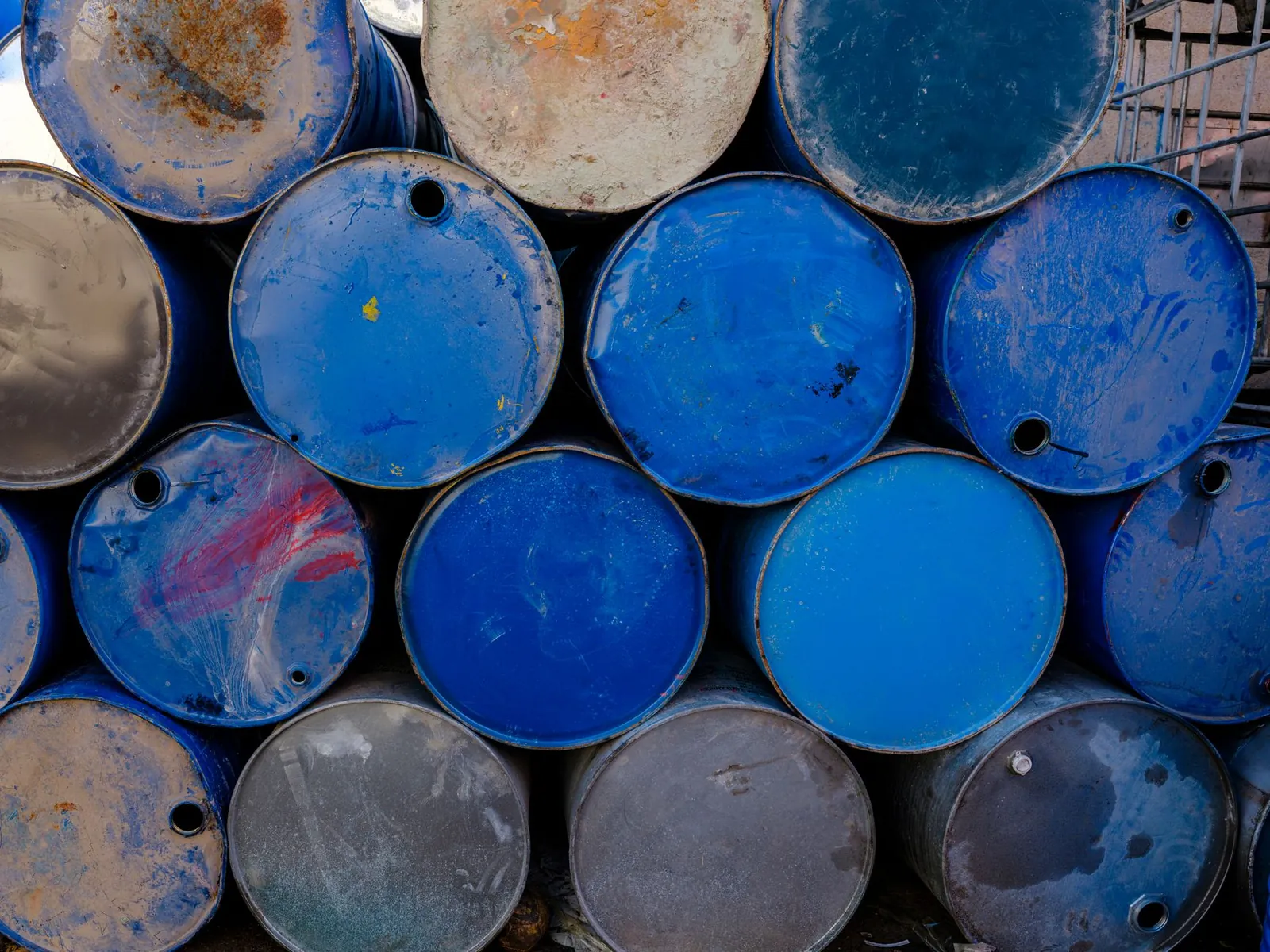 A collection of blue metal drums stacked outdoors, highlighting industrial recycling. Stock photo illustrating East India Drums and Barrels Manufacturing's new order story.