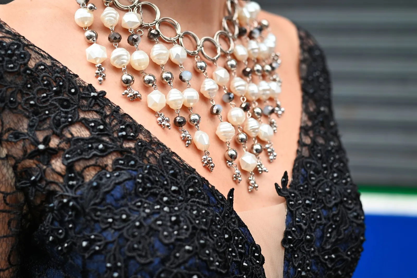 Detailed shot of an intricate pearl necklace on a black lace dress for fashion and accessory focus. Stock photo illustrating PNGS Gargi Fashion Jewellery's earning call story.