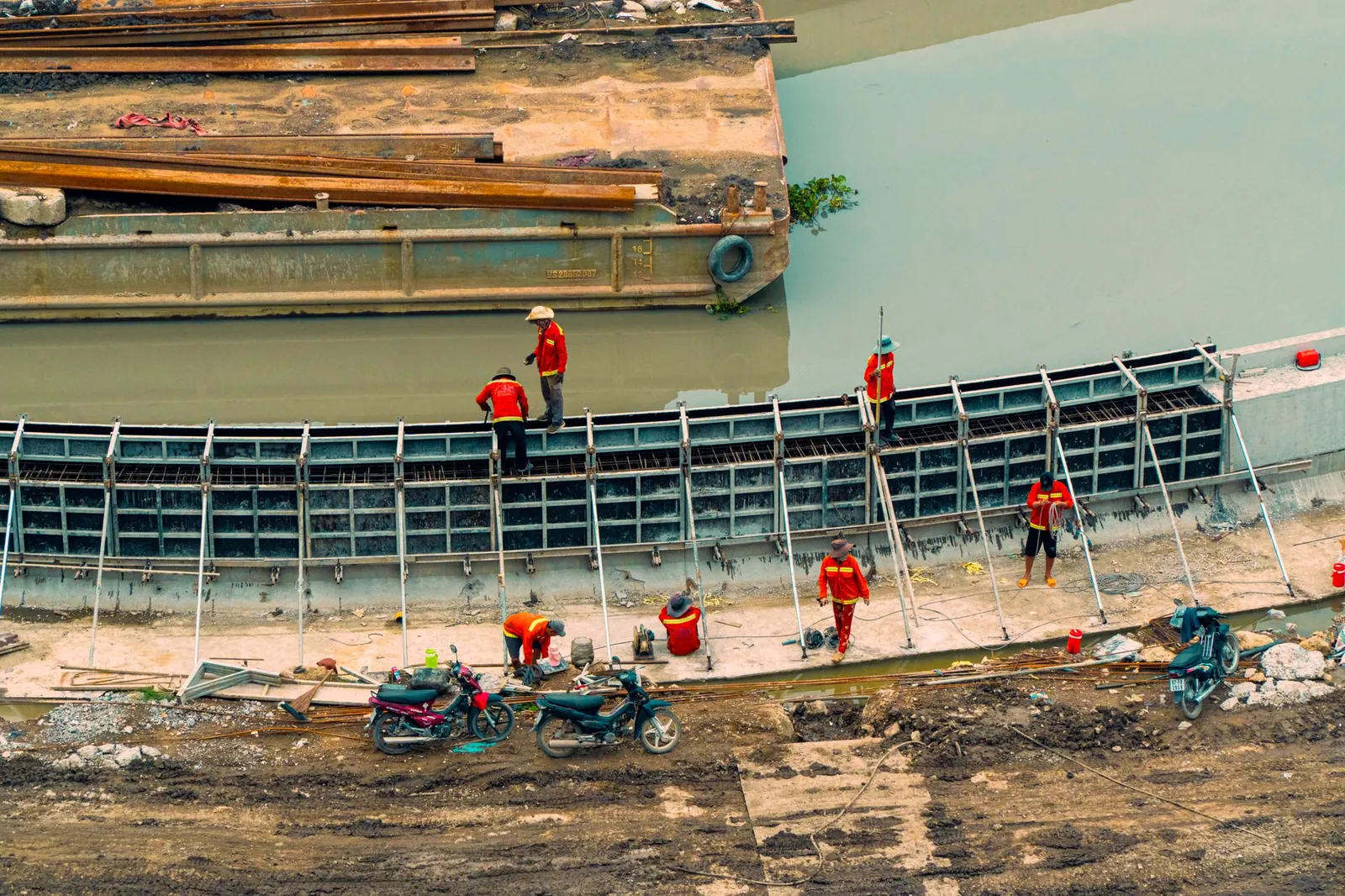 Aerial view of construction workers building canal infrastructure with visible equipment and waterway. Stock photo illustrating Sattva Engineering Construction's new order story.