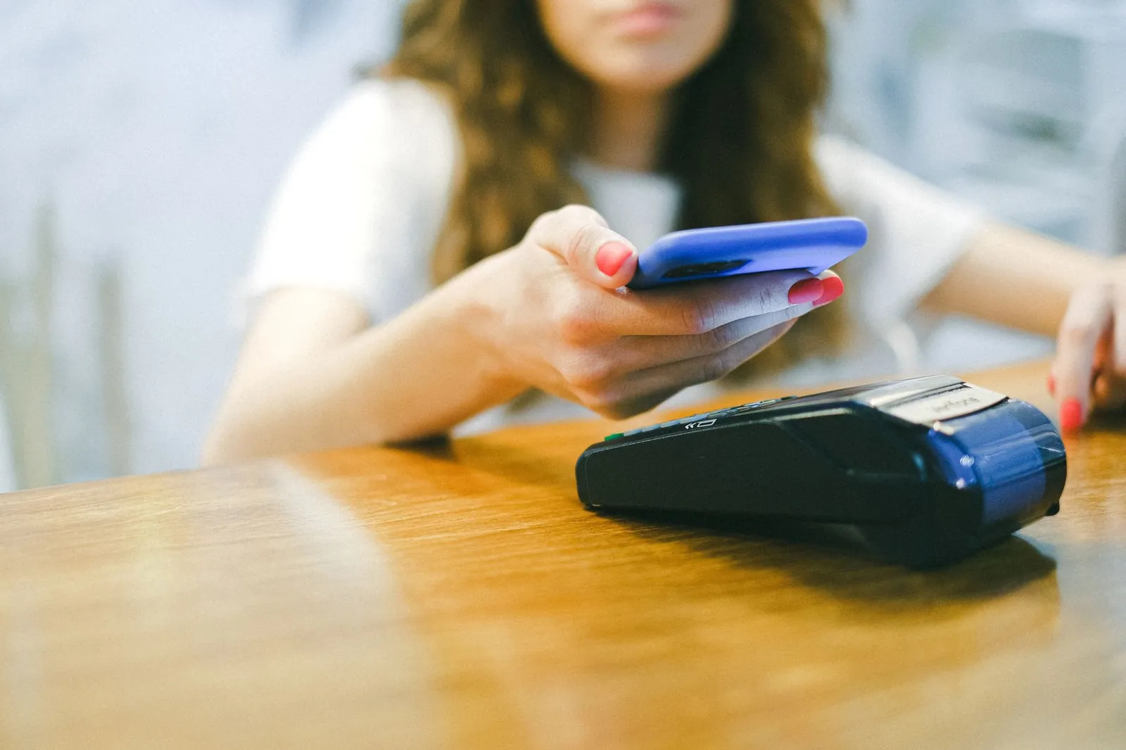 A woman processes a contactless payment using her smartphone at a payment terminal. Stock photo illustrating Mos Utility's regulatory approval story.