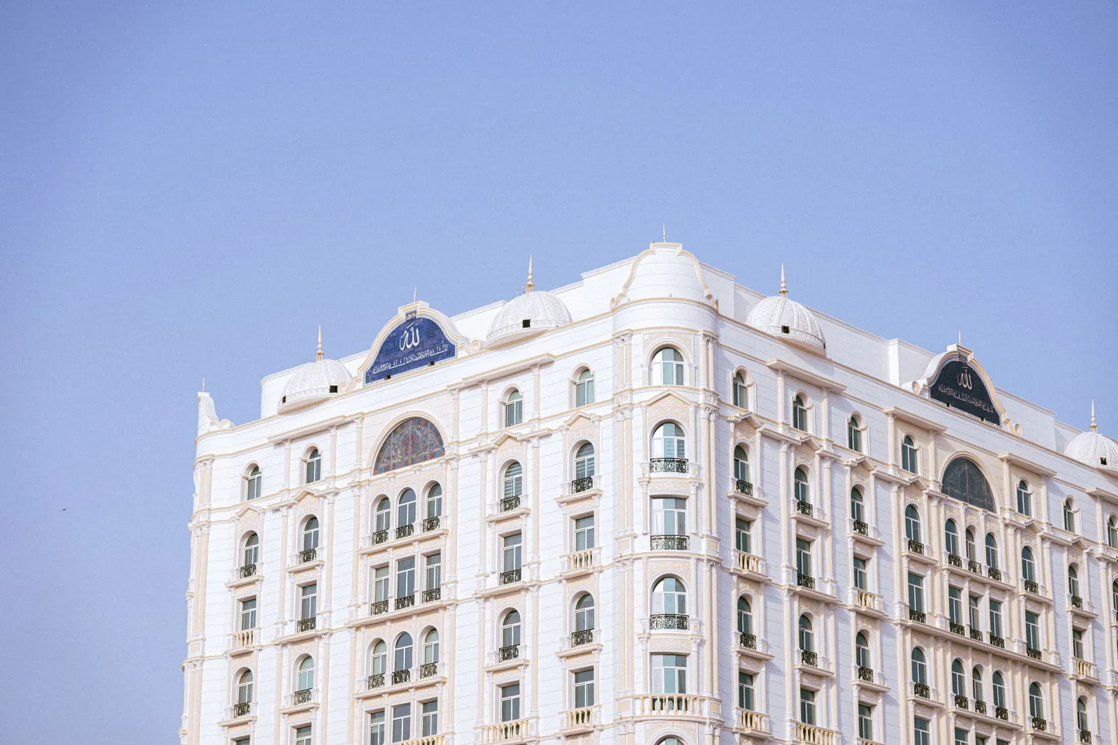 A luxurious white hotel facade with classic architecture under a clear blue sky. Stock photo illustrating Sayaji Hotels (Pune)'s expansion story.