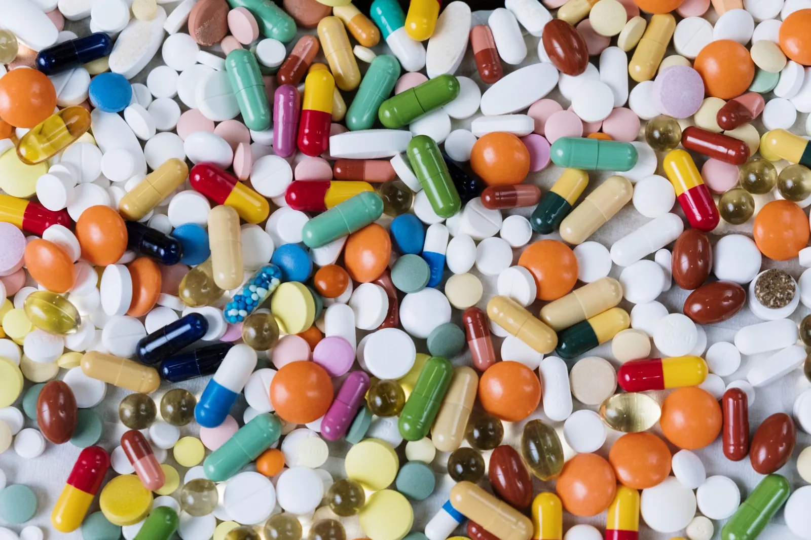 Vibrant assortment of medicine capsules and tablets in a flatlay format, highlighting diversity in pharmaceuticals. Stock photo illustrating Natural Capsules' fund raise story.