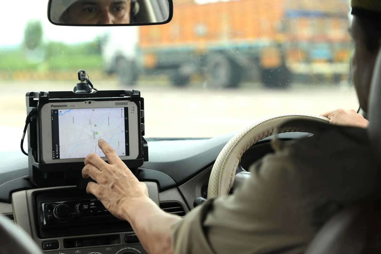Police officer navigates using a digital map on a tablet inside a vehicle. Stock photo illustrating Delhivery's product launched story.