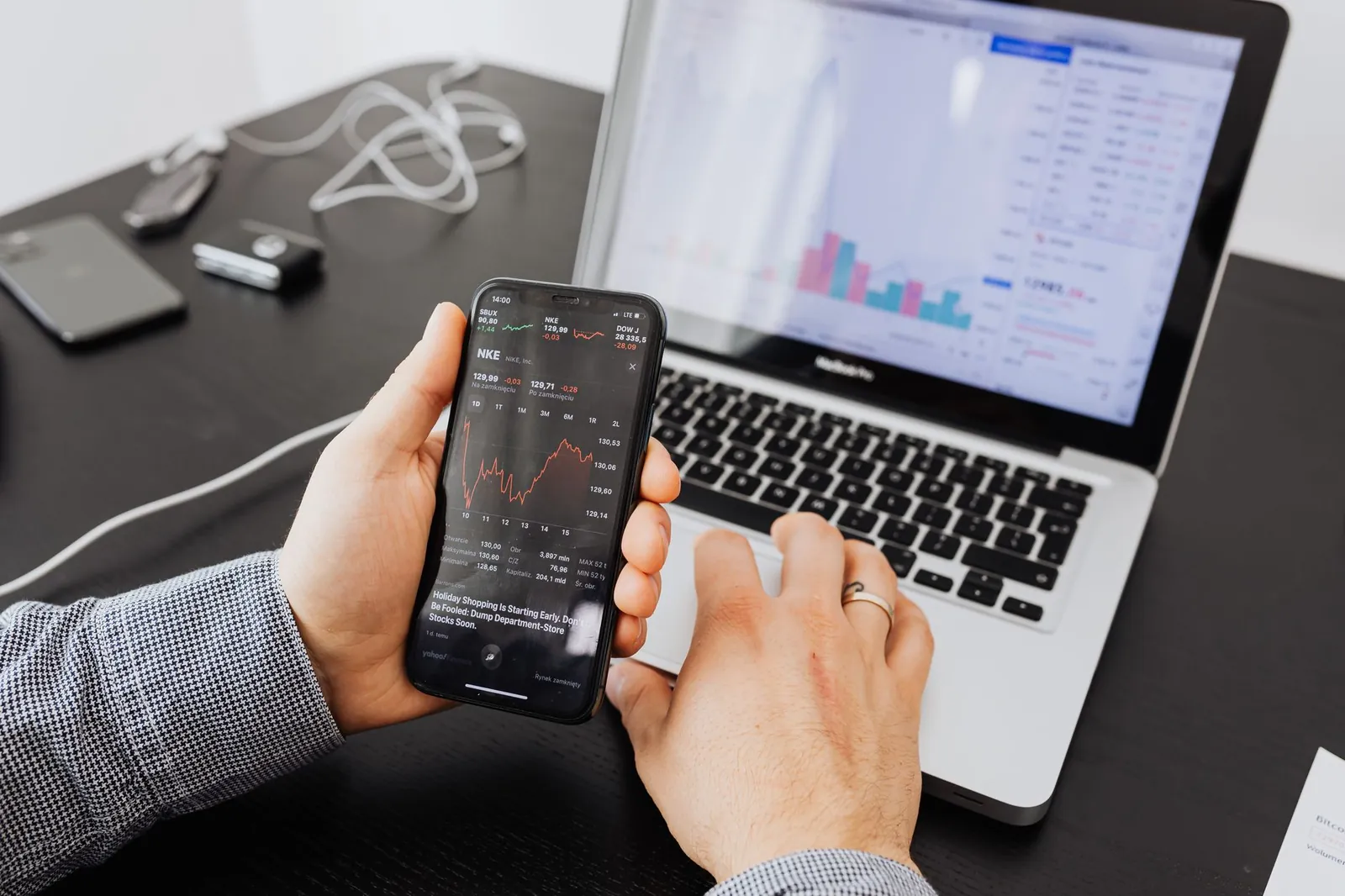 Person analyzes stock data with a smartphone and laptop, indoors. Stock photo for the ALFA News guide: How to Analyse an Earnings Call: A Guide for Indian Investors.