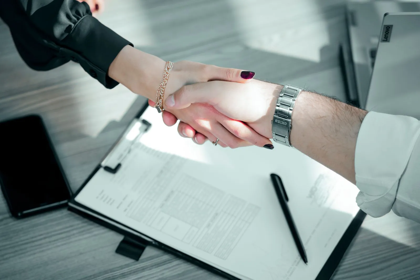 Close-up of a professional handshake over a contract, symbolizing a successful business deal. Stock photo for the ALFA News guide: What L1 Bidder Means: SEBI Rules and Stock Market Implications.