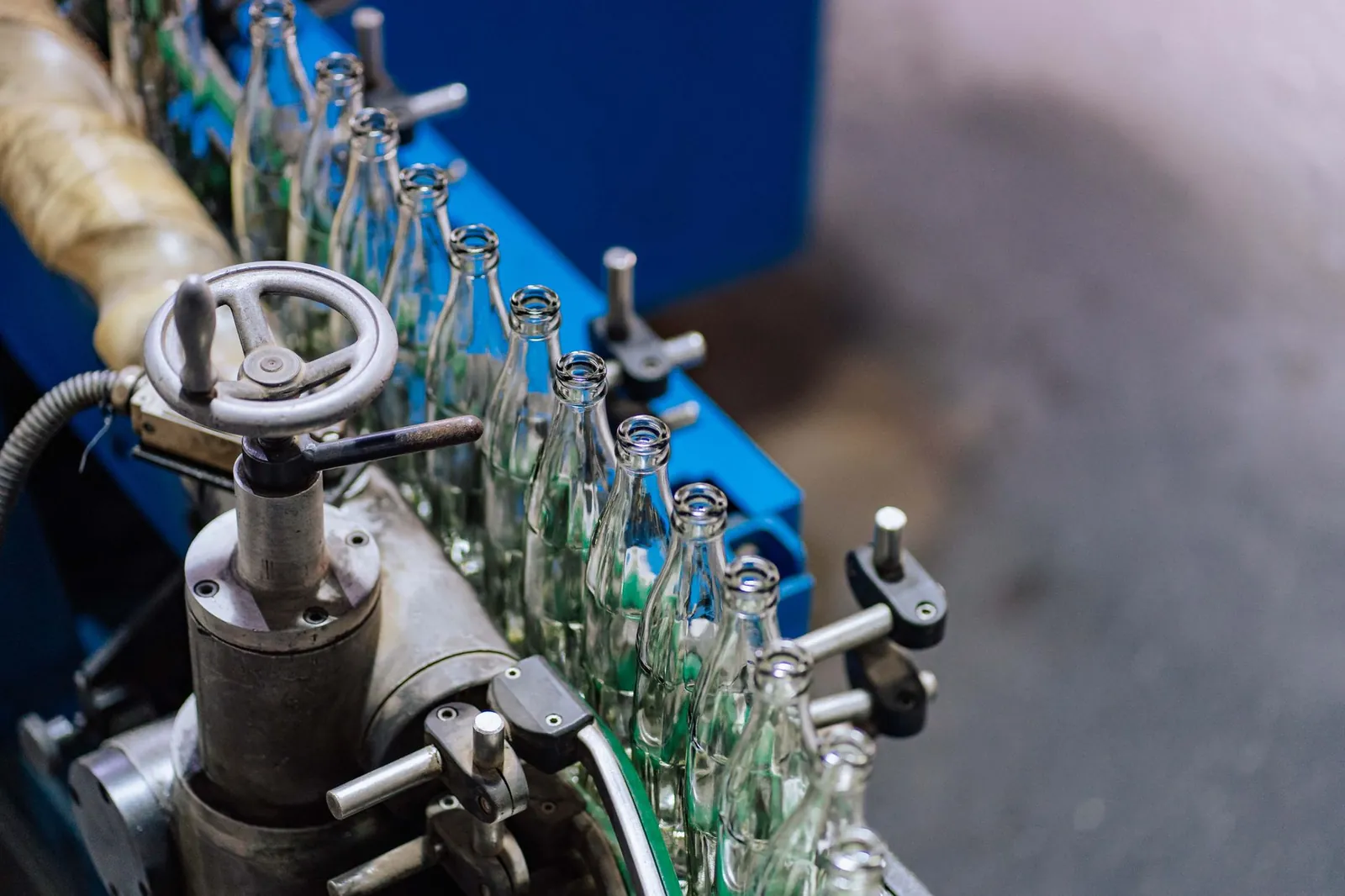 Close-up of glass bottling machinery in action, showcasing industrial precision. Stock photo illustrating Tilaknagar Industries' production started story.