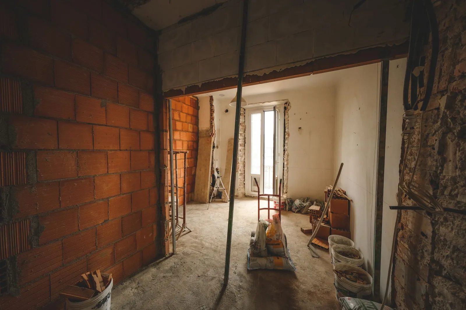 A partially renovated room with exposed brick walls and construction materials on site. Stock photo illustrating Agi Infra's fund raise story.