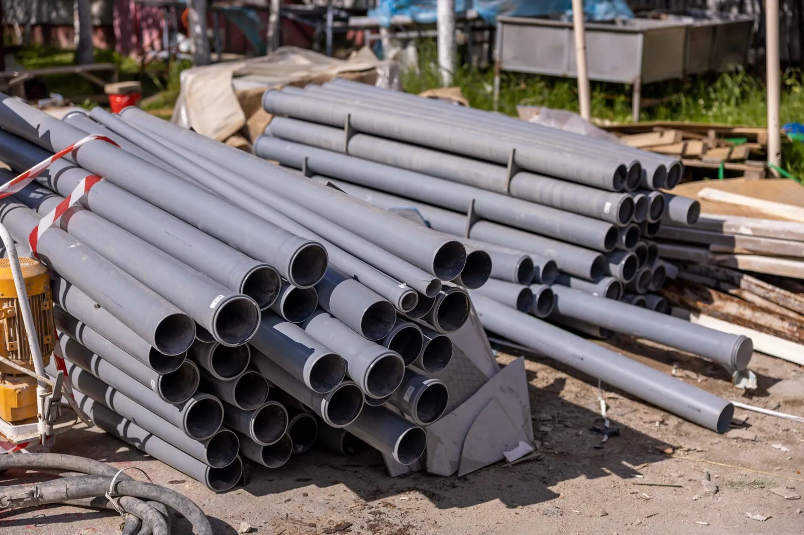 A collection of gray PVC pipes neatly stacked at an outdoor construction site. Stock photo illustrating Apollo Pipes' expansion story.