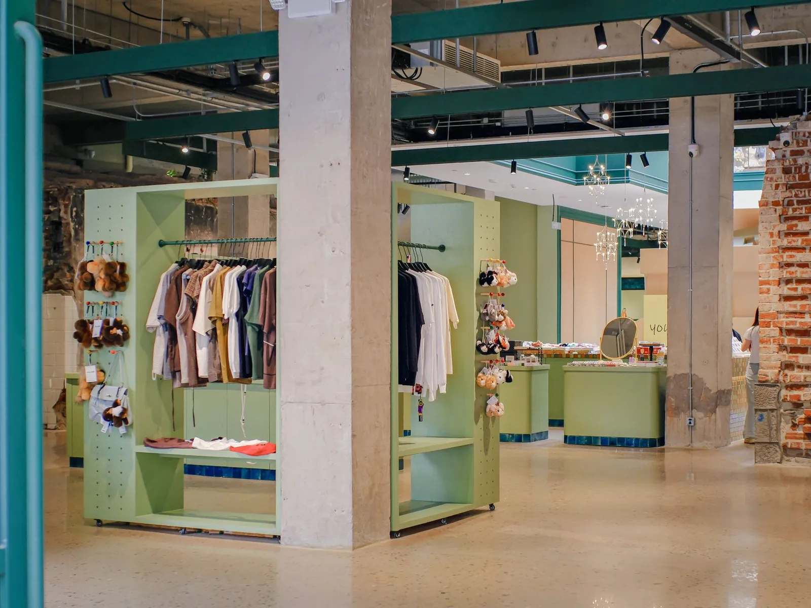 A contemporary store interior featuring minimalist green displays with hanging clothing and plush toys. Stock photo illustrating Iris Clothings' partnership story.