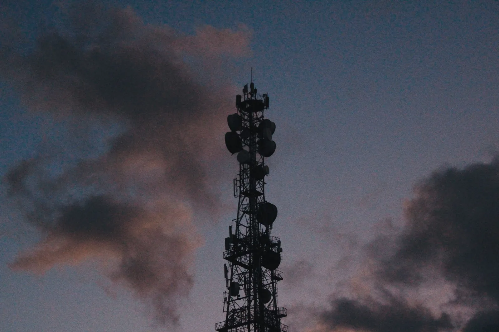 Silhouette of a telecommunications tower against a vibrant twilight sky with clouds. Stock photo illustrating Methodhub Software's new order story.