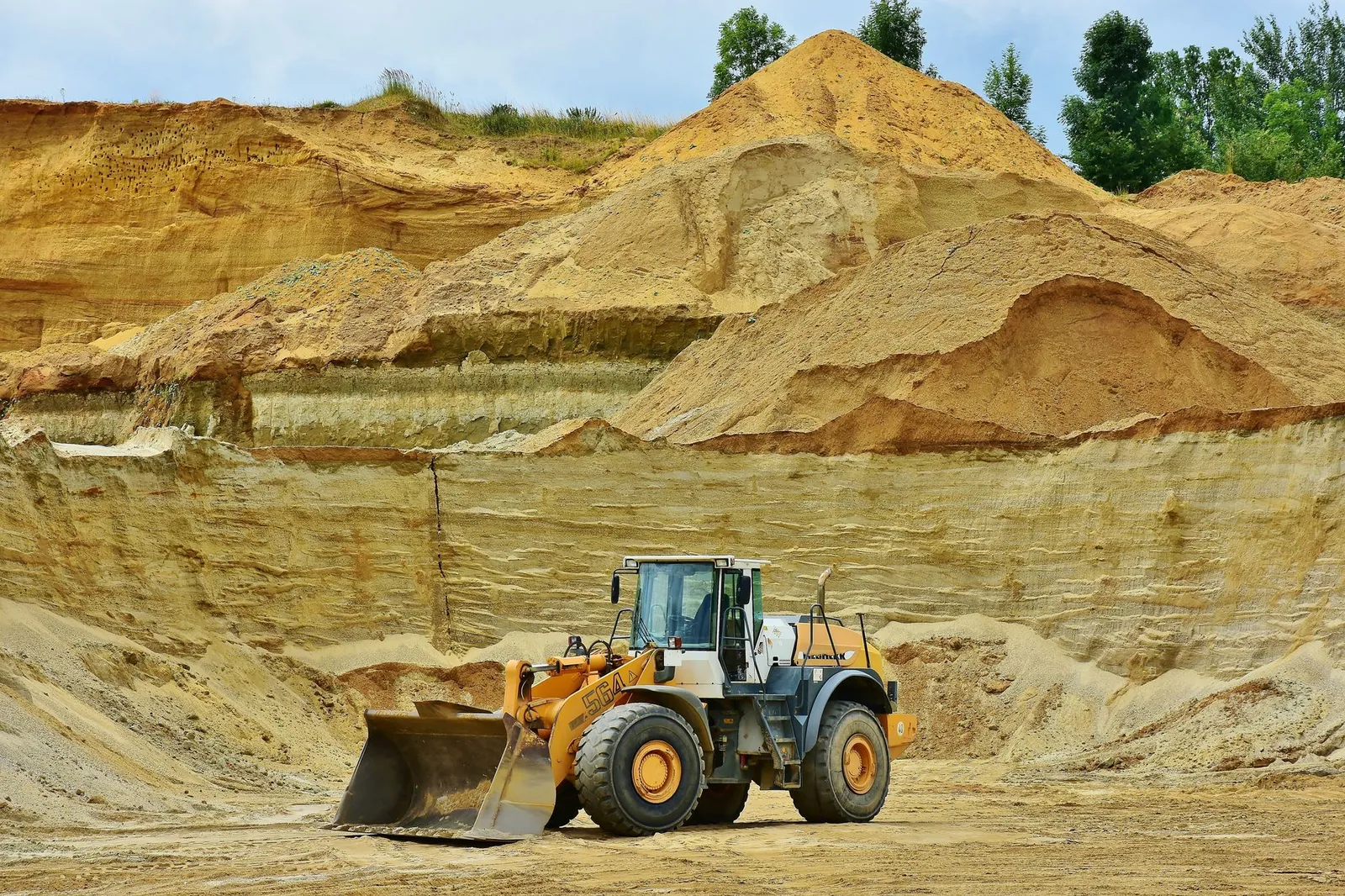 An excavator working in an open pit mine surrounded by sandy terrain and clear sky. Stock photo illustrating KNR Constructions' new order story.