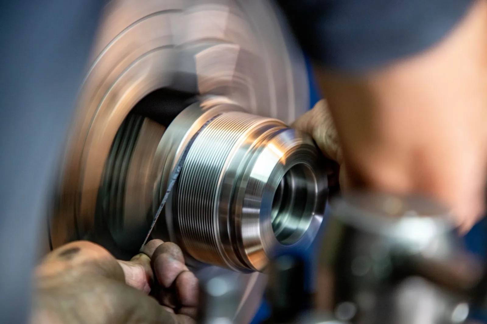 Close-up view of a worker grinding metal, showcasing precision and craftsmanship in industrial setting. Stock photo illustrating OBSC Perfection's earning call story.