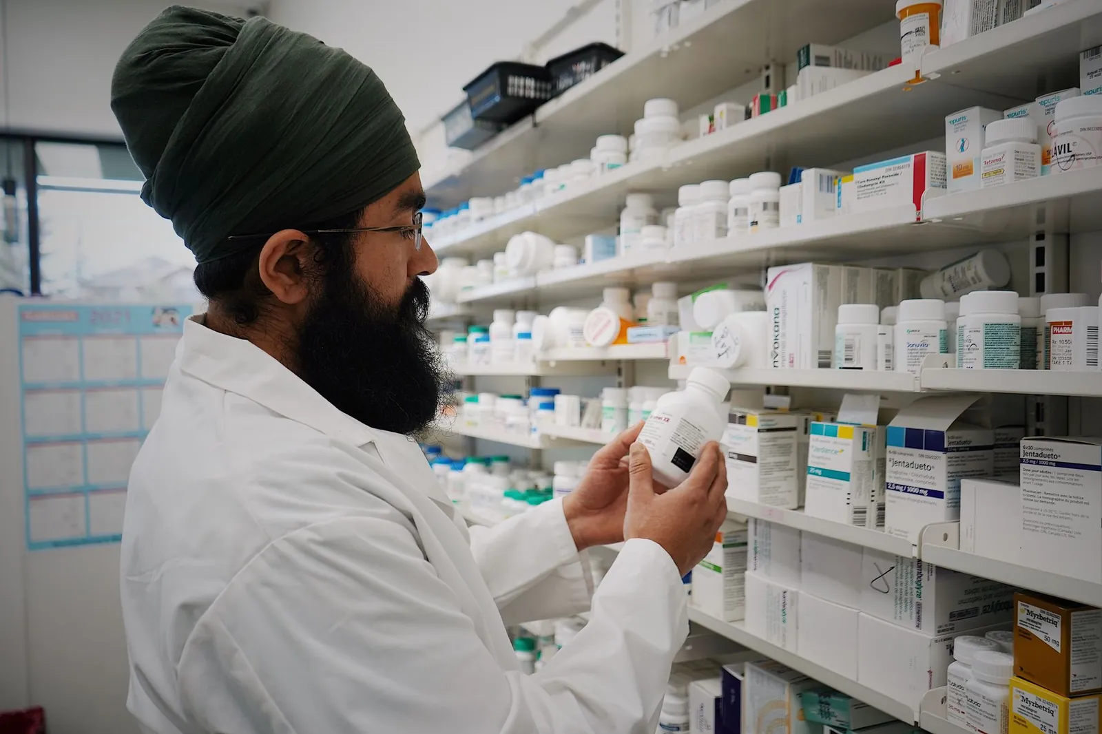 Pharmacist with turban organizing shelves in a pharmacy, focused on healthcare. Stock photo illustrating Solara Active Pharma Sciences' financial results story.
