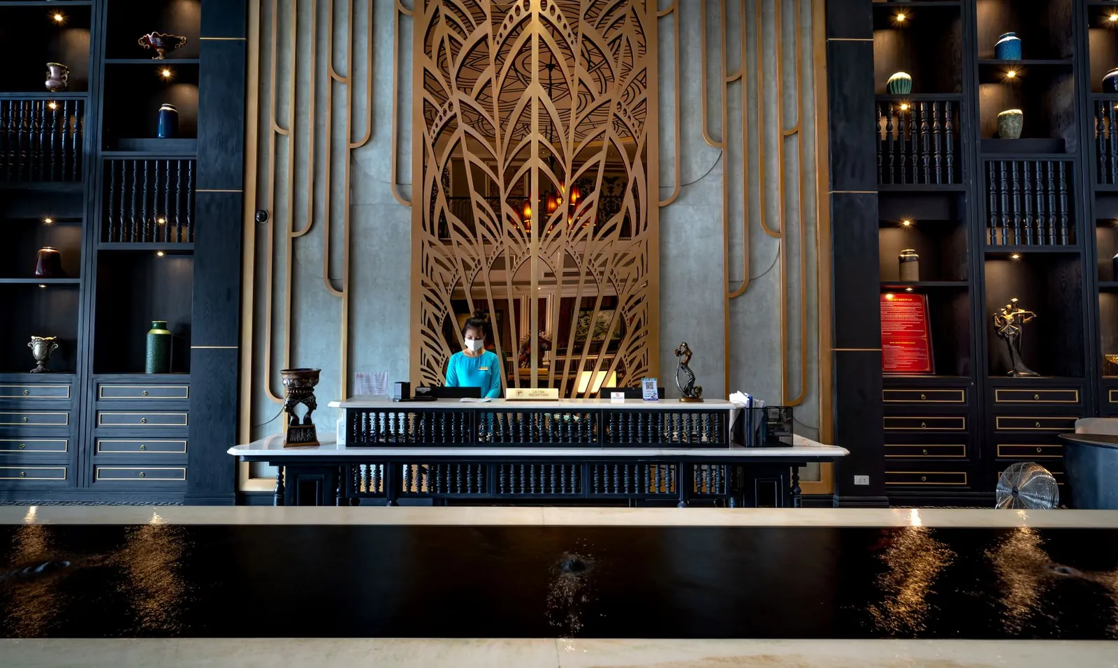 Elegant hotel reception with a modern design, featuring a receptionist at the front desk, ornate decor, and luxury ambiance. Stock photo illustrating Viceroy Hotels' fund raise story.