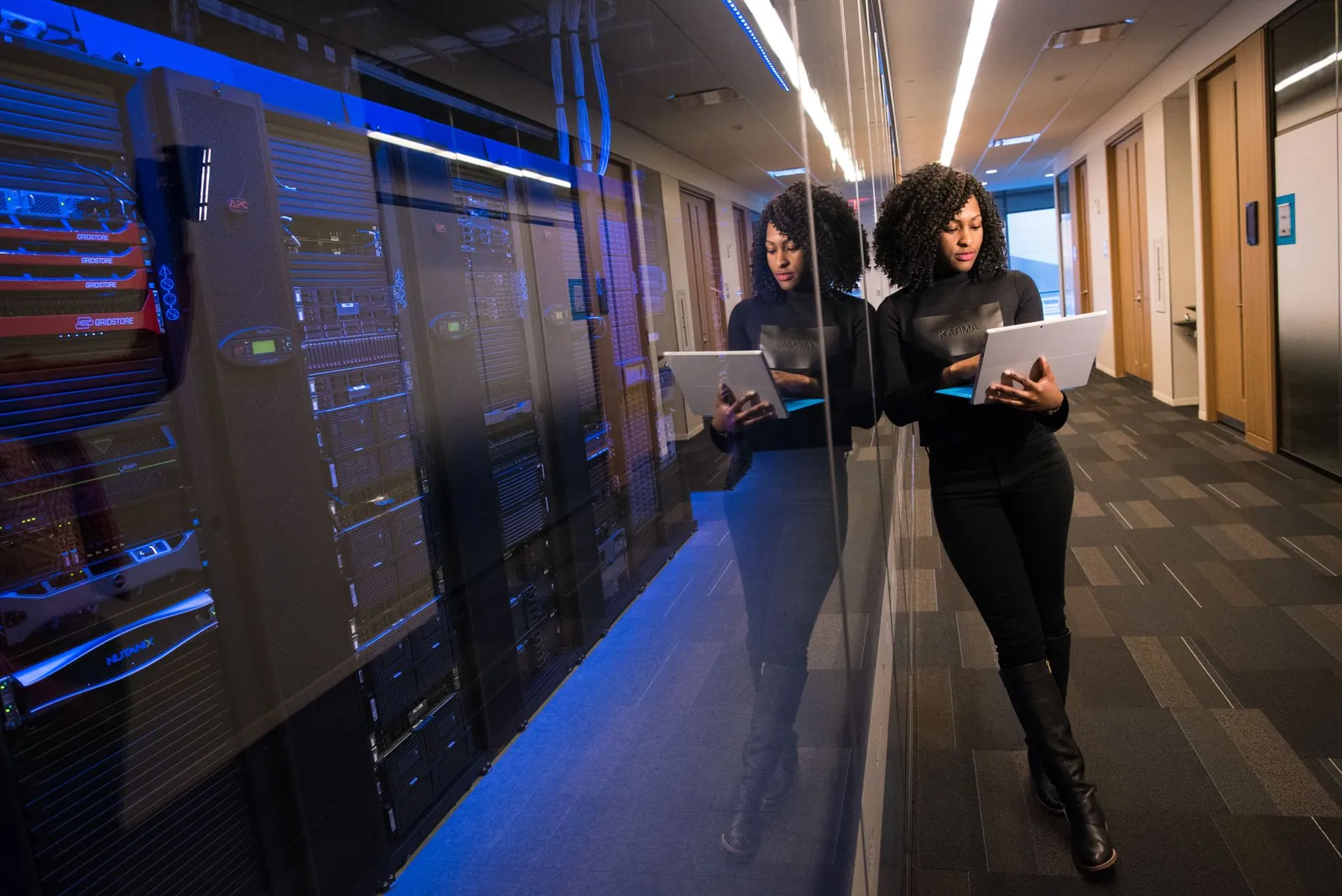 A woman using a laptop navigating a contemporary data center with mirrored servers. Stock photo illustrating Belding India's partnership story.