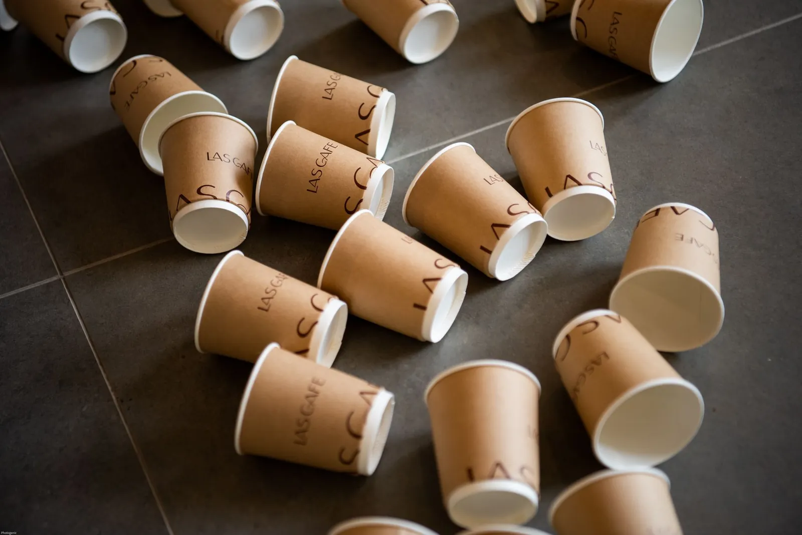 Multiple branded disposable paper cups scattered on a tile floor, symbolizing waste. Stock photo illustrating Aaradhya Disposal Industries' fund raise story.