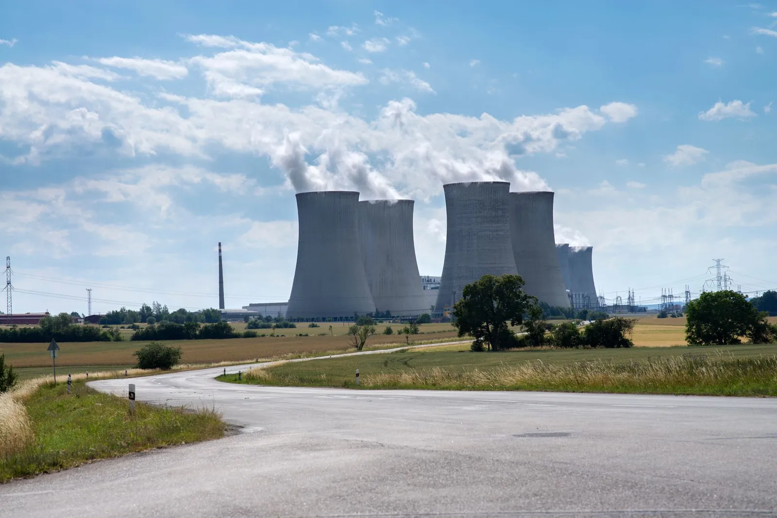 Cooling towers of Dukovany Nuclear Power Plant on a sunny day with smoke rising. Stock photo illustrating Advait Energy Transitions' earning call story.