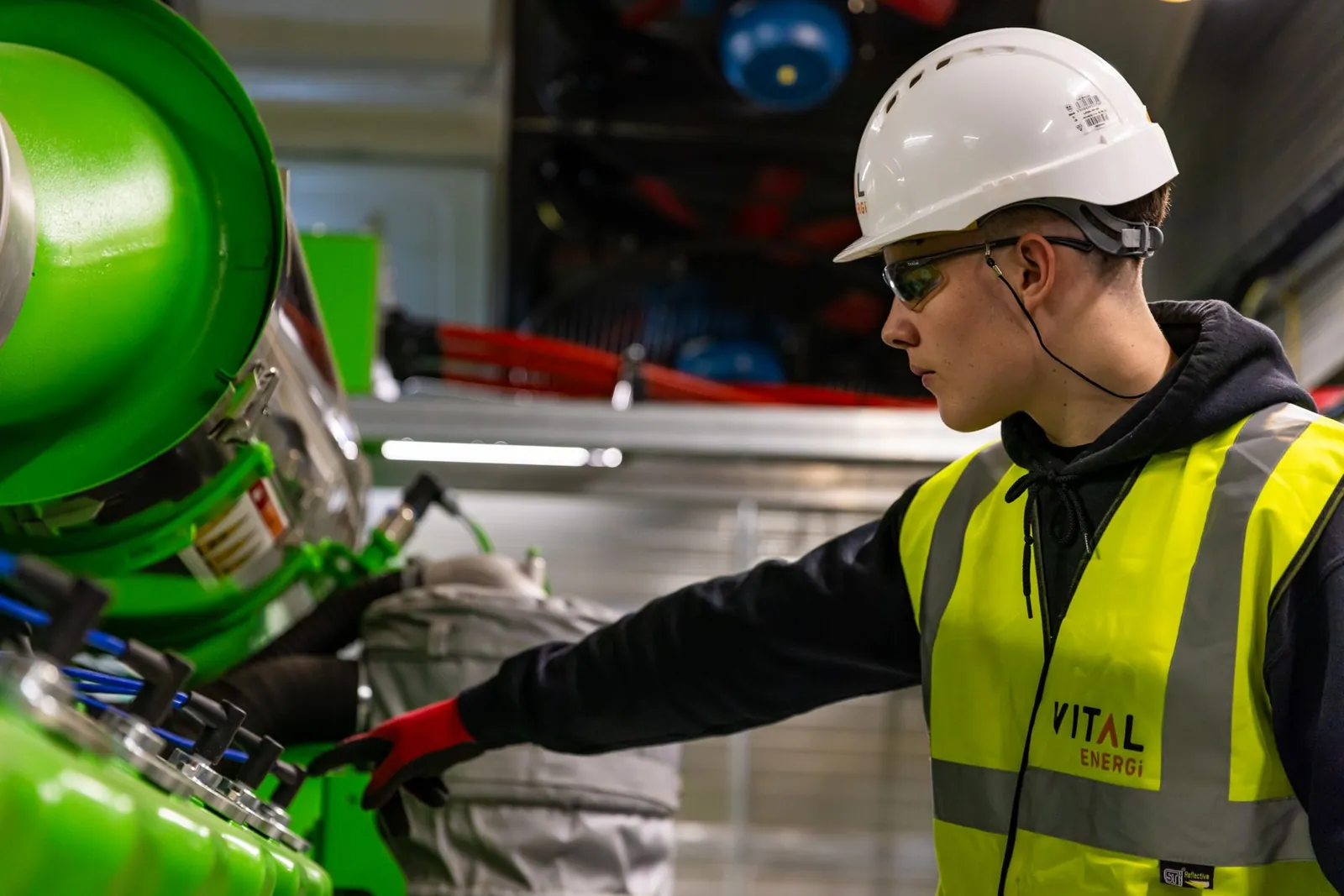 Safety-focused worker operating machinery indoors, wearing protective gear. Stock photo illustrating Bluspring Enterprises' new order story.