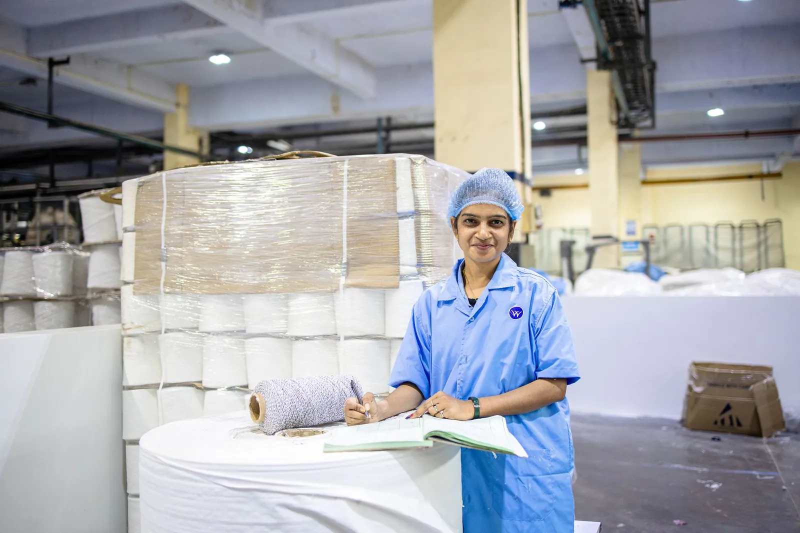 Female worker in textile factory checking yarn rolls, showcasing industry precision. Stock photo illustrating KS Smart Technologies' fund raise story.