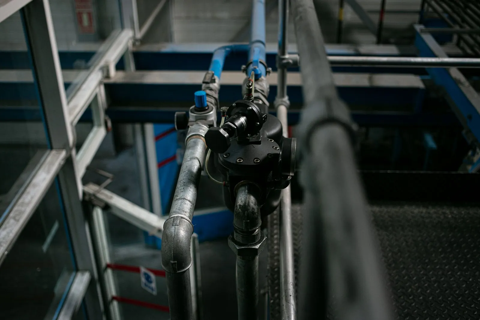 Detailed view of a metallic pipe system with valves in an industrial setting. Stock photo illustrating Captain Polyplast's production started story.