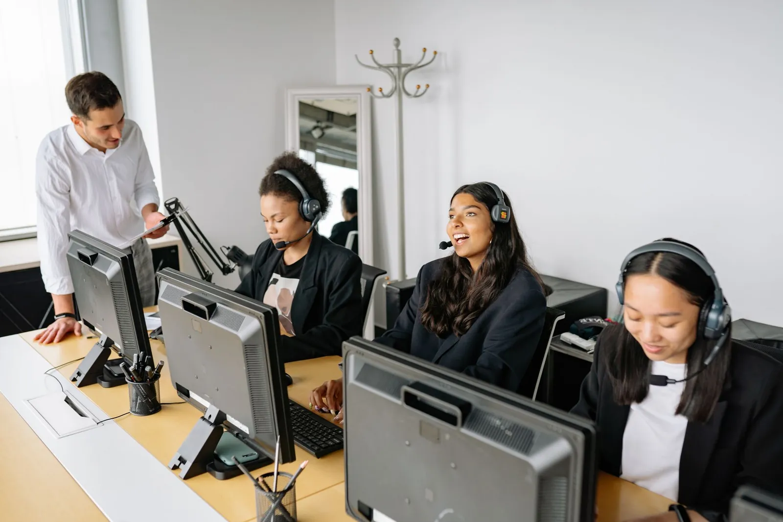 A diverse team of customer service representatives working in an office setting, wearing headsets and using computers. Stock photo illustrating Exato Technologies' new order story.