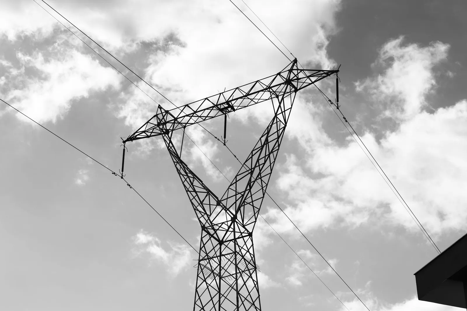 A high voltage power line towering against a dramatic cloudy sky in a black and white composition. Stock photo illustrating Bajel Projects' new order story.