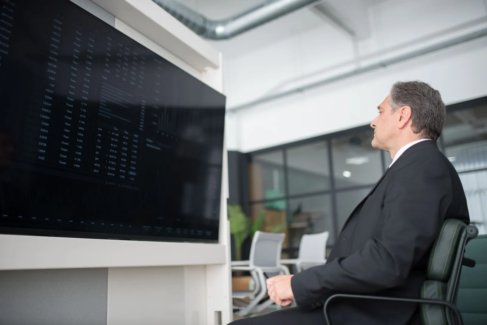A professional businessman in a modern office analyzing stock market data on a large screen. Stock photo illustrating KFin Technologies' product launched story.