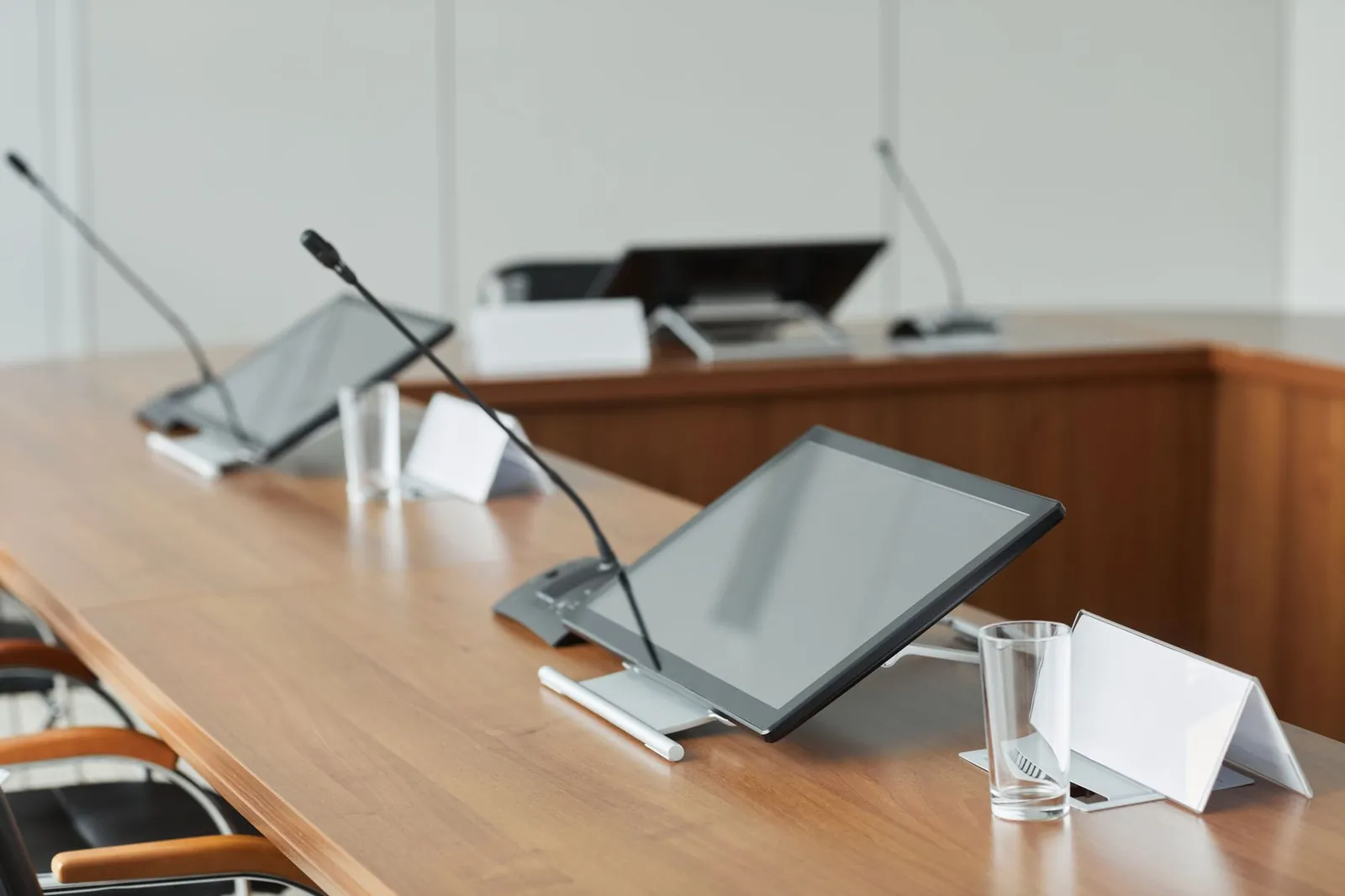 A modern conference room featuring sleek monitors and microphones on a wooden tabletop, perfect for meetings. Stock photo illustrating Crescentis Capital's fund raise story.