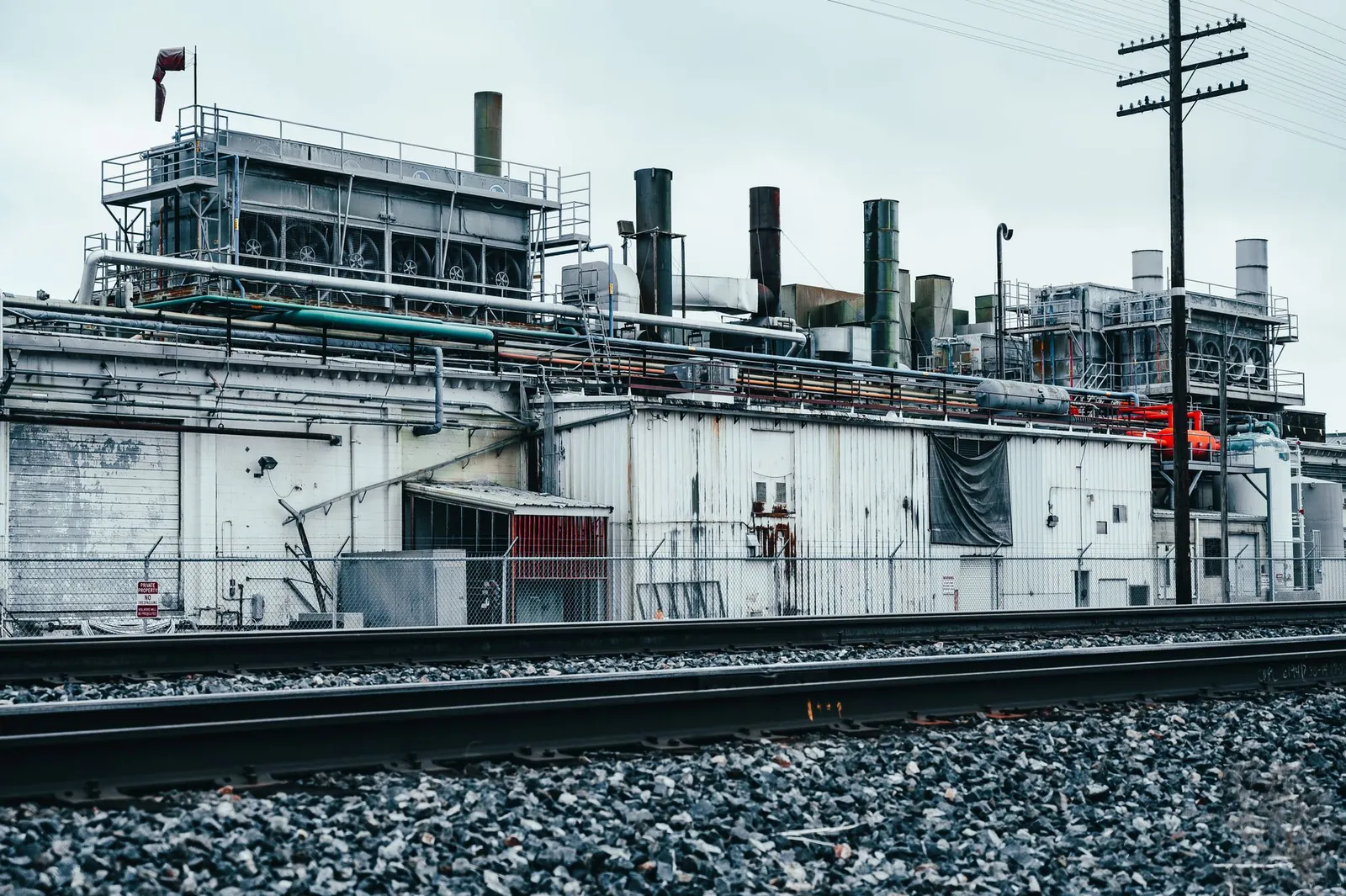 Aged industrial factory with shabby walls and pipes located near railroad station against cloudy sky. Stock photo illustrating Pace Digitek's new order story.