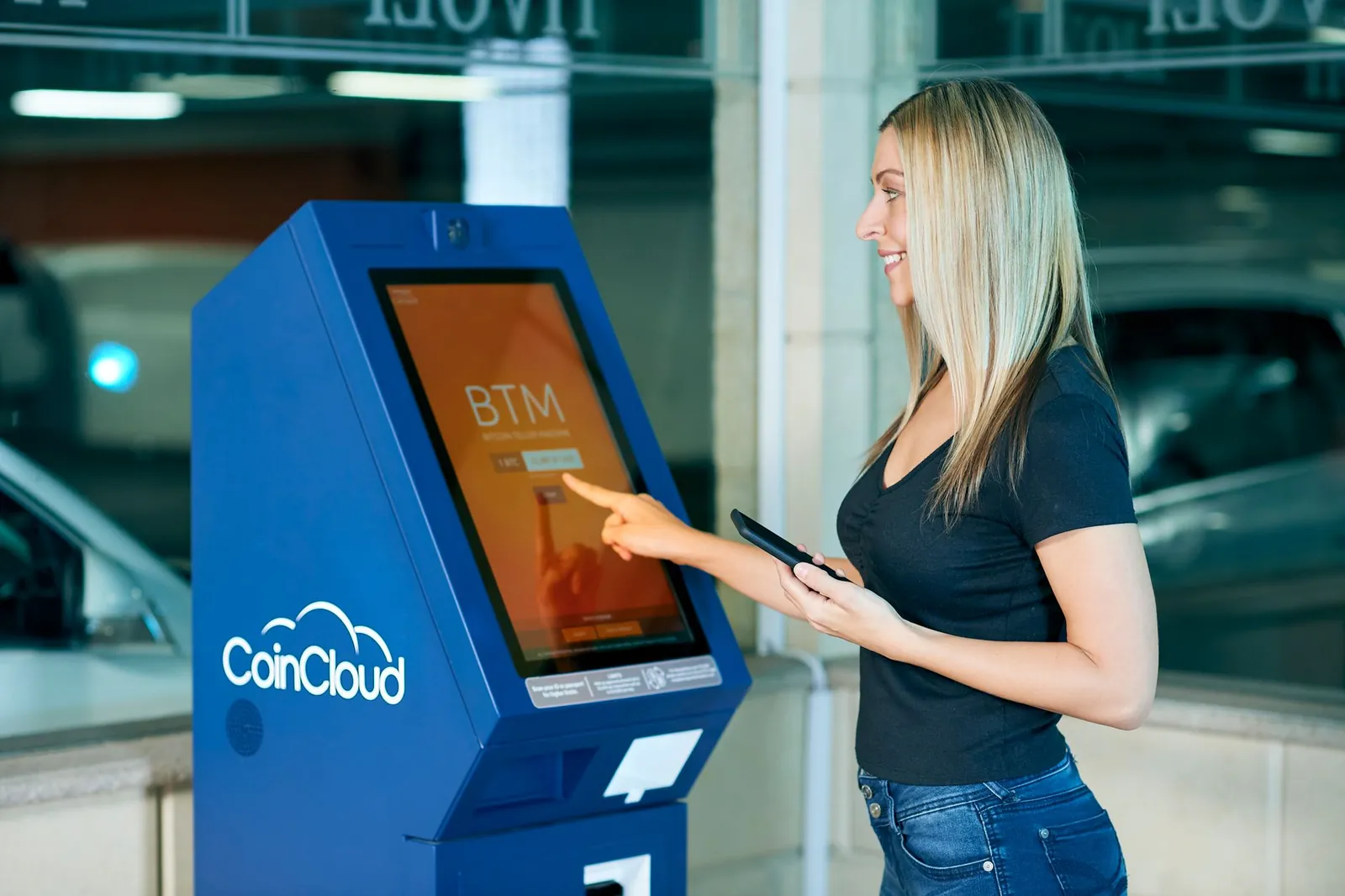 A woman interacts with a CoinCloud machine indoors, showcasing modern digital banking. Stock photo illustrating Network People Services Technologies' earning call story.