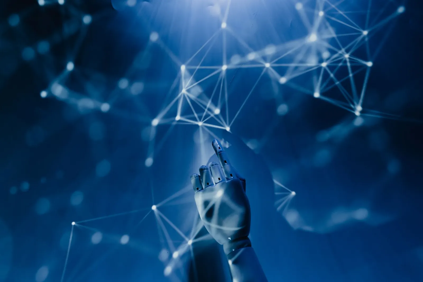 A robotic hand reaching into a digital network on a blue background, symbolizing AI technology. Stock photo illustrating LTM's product launched story.