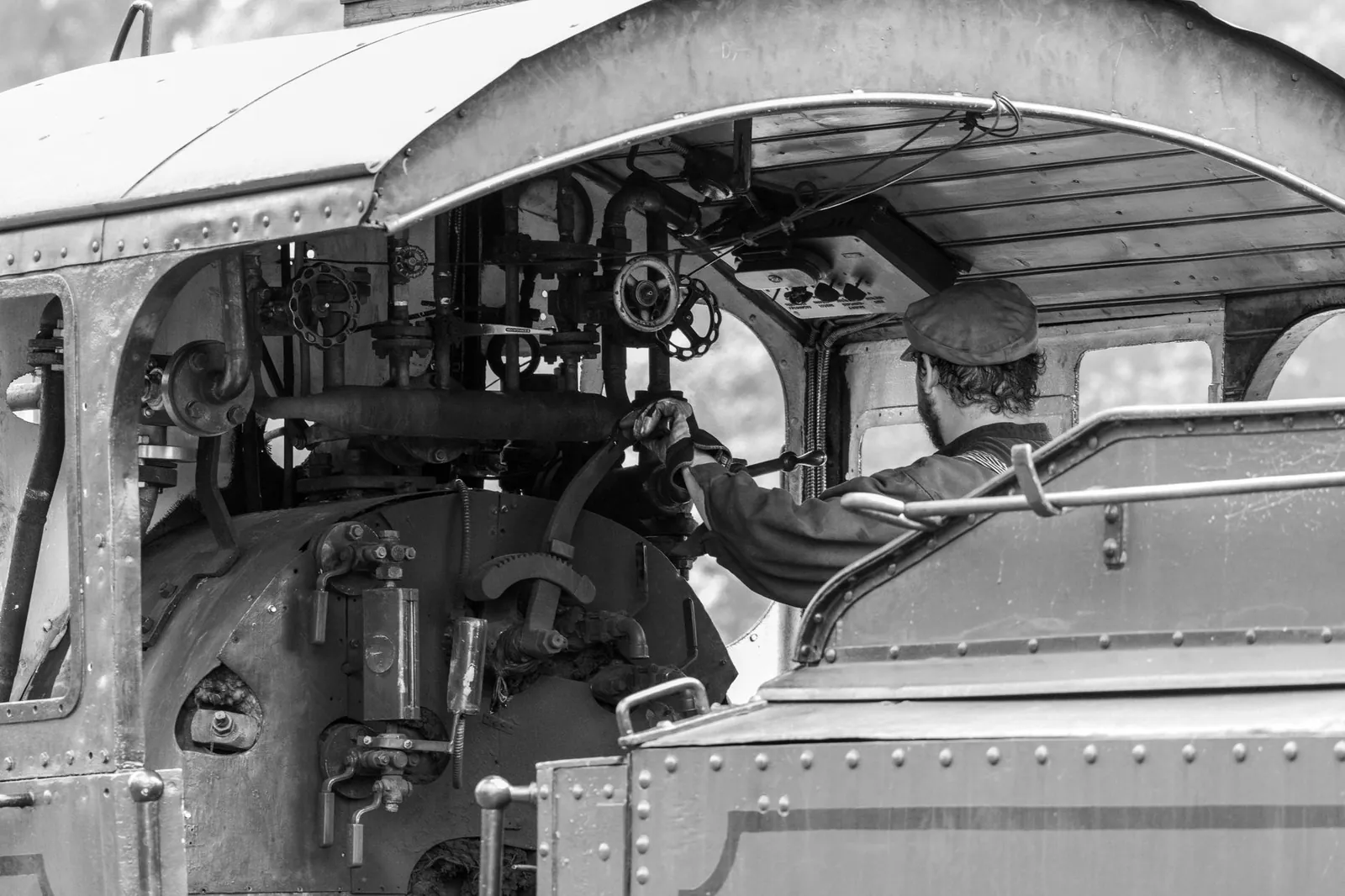 A vintage train engineer works in the steam locomotive's cabin, captured in black and white. Stock photo illustrating Kernex Microsystems (India)'s new order story.