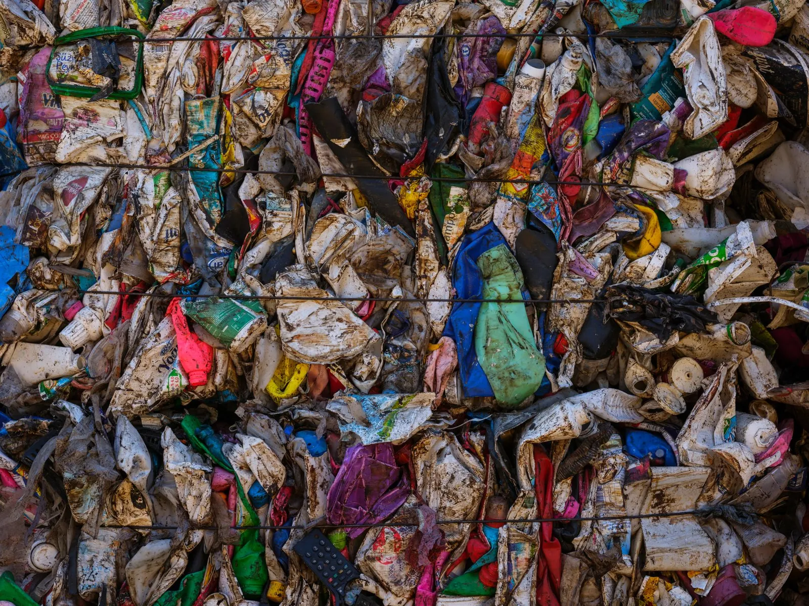 A visually striking wall of compressed, multicolored plastic waste highlighting recycling and consumerism concerns. Stock photo illustrating Rain Industries' partnership story.