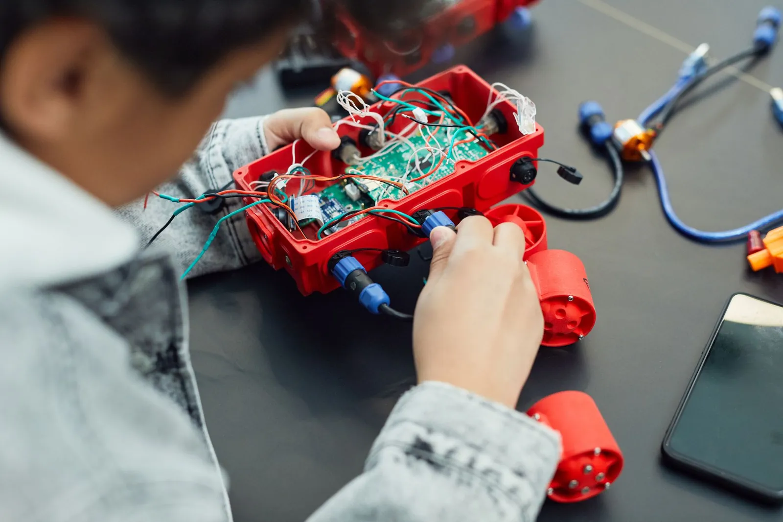 A child actively assembling a robotics project with electronic components, showcasing technology education. Stock photo illustrating Avalon Technologies' earning call story.