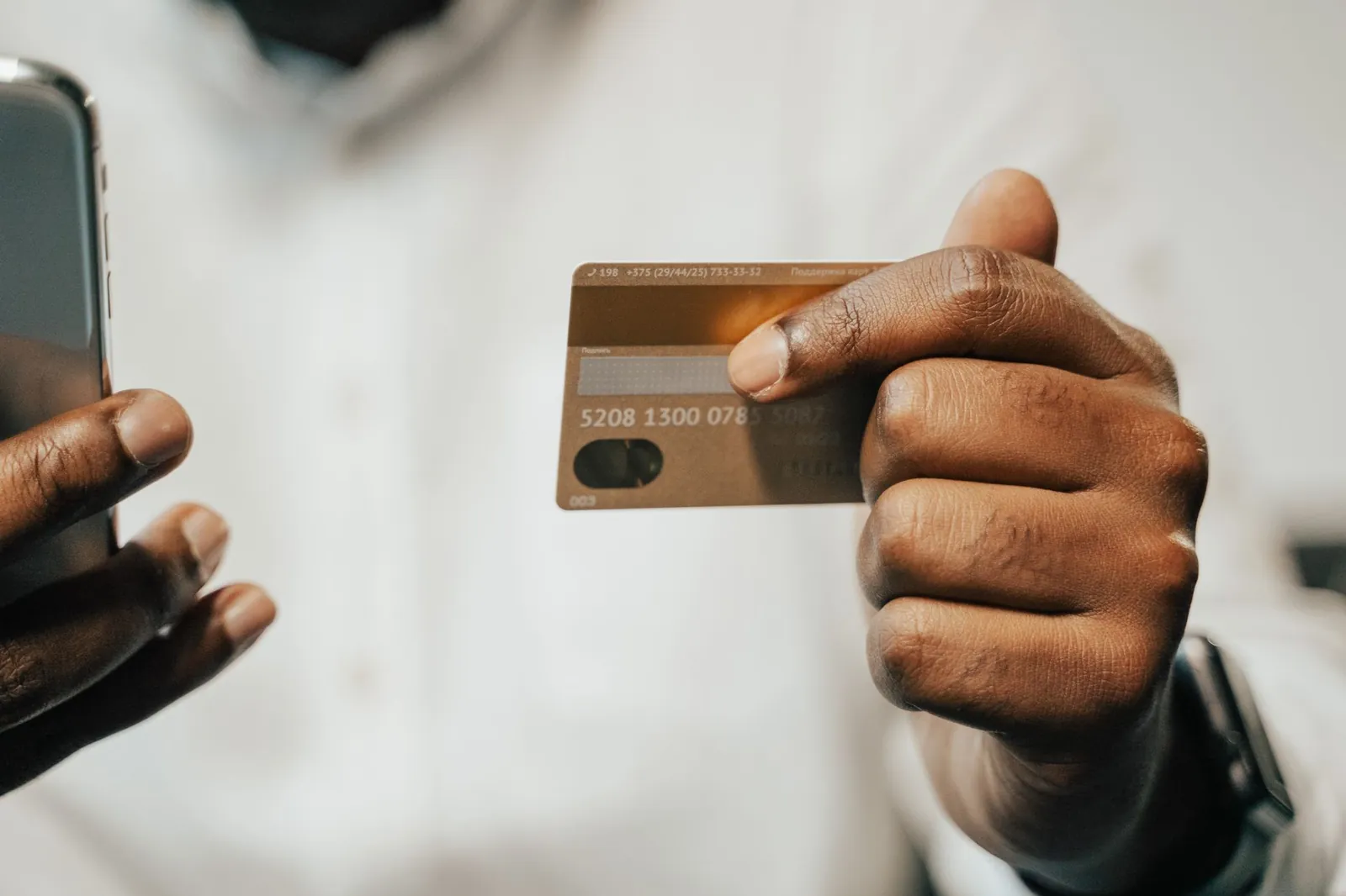 Person using a smartphone and credit card for online shopping or payment. Stock photo illustrating Thomas Cook (India)'s product launched story.