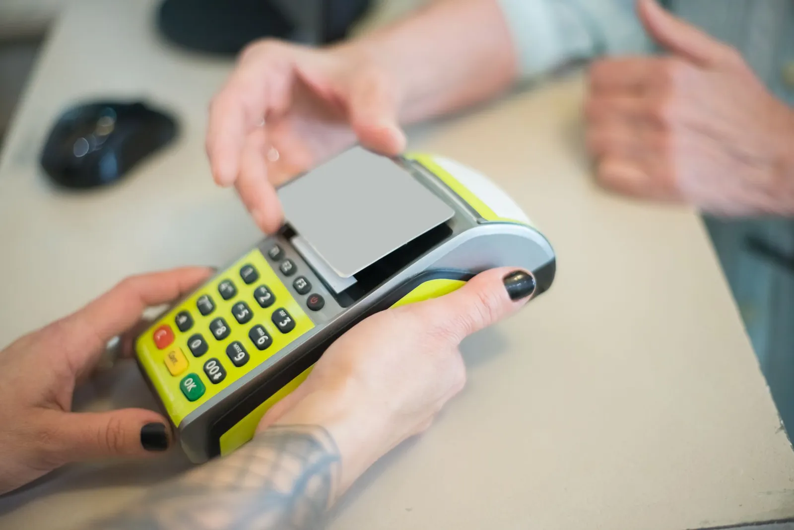 Hands engaging in a secure card transaction with a payment terminal, capturing the essence of modern business transactions. Stock photo illustrating IndusInd Bank's product launched story.