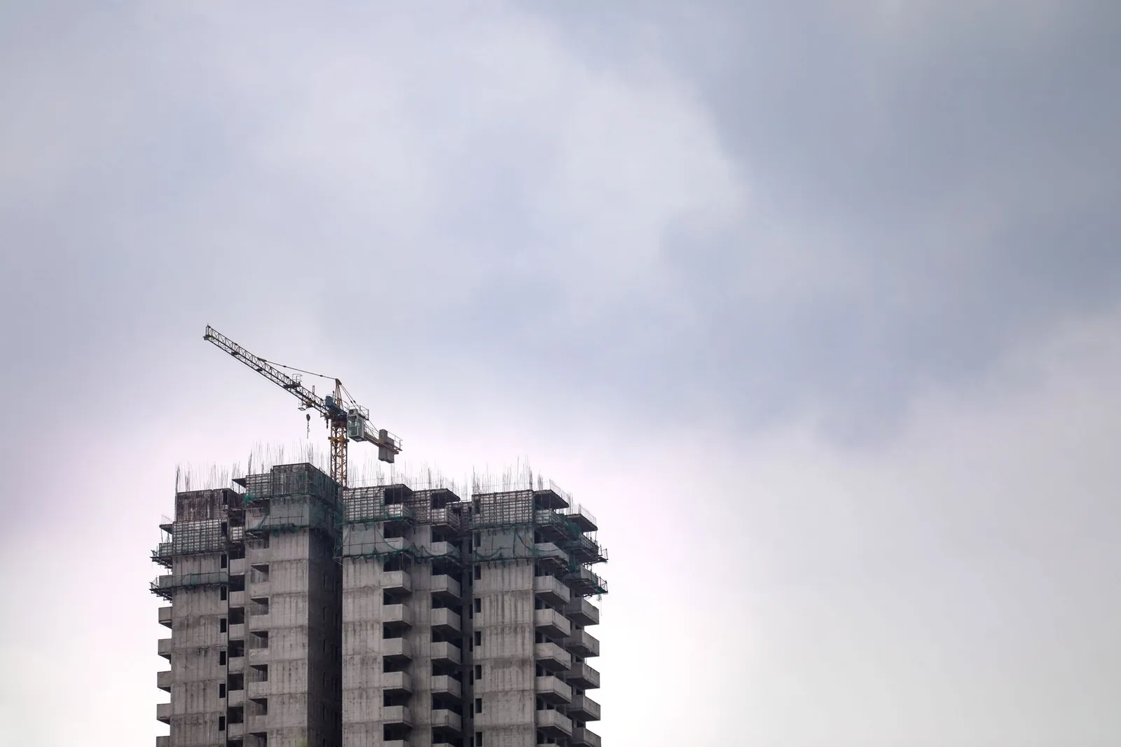 High-rise building construction site with crane against a cloudy sky, showcasing urban development. Stock photo illustrating Chavda Infra's new order story.