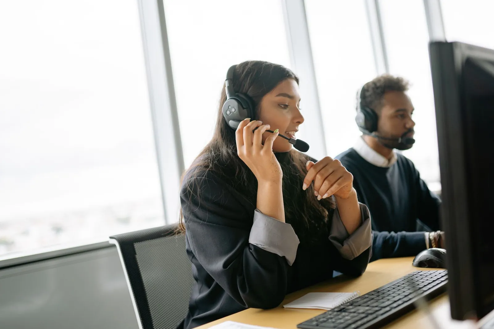 Customer service agents using headsets and computers in a modern office environment. Stock photo illustrating Coforge's product launched story.