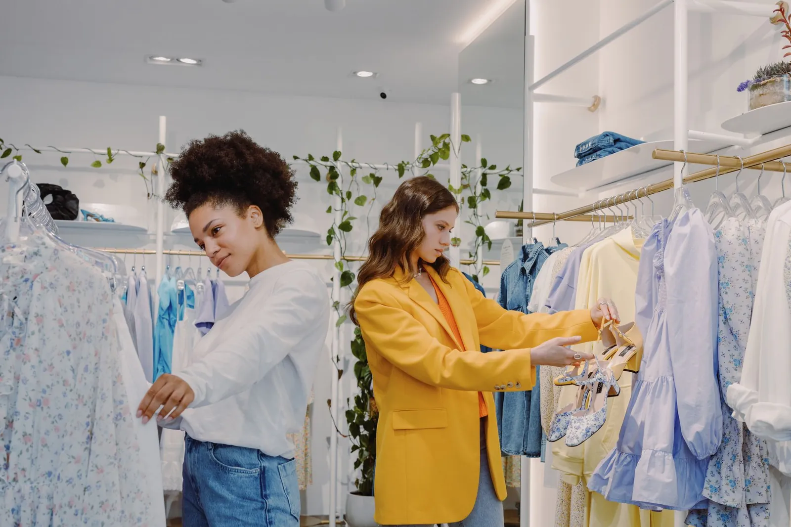 Two women shopping in a trendy clothing store, browsing stylish outfits. Stock photo illustrating Baazar Style Retail's expansion story.