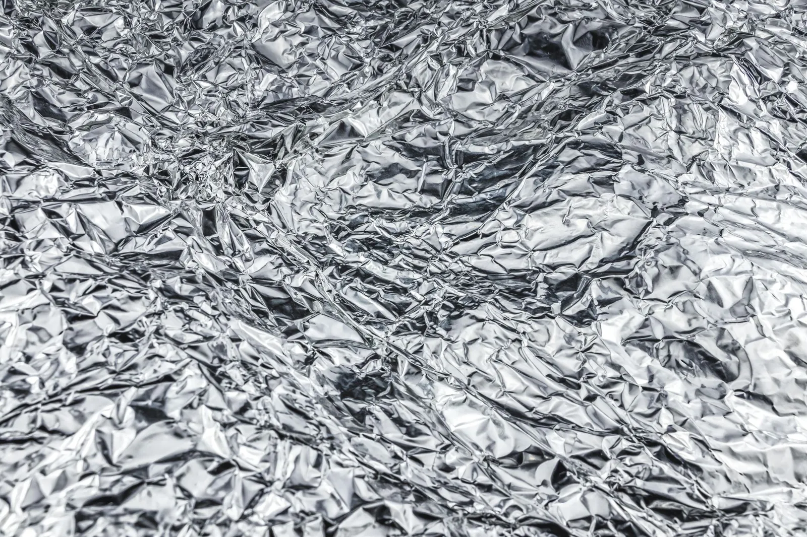 Close-up of crumpled aluminum foil creating a shiny, textured surface. Stock photo illustrating Arfin India's new order story.