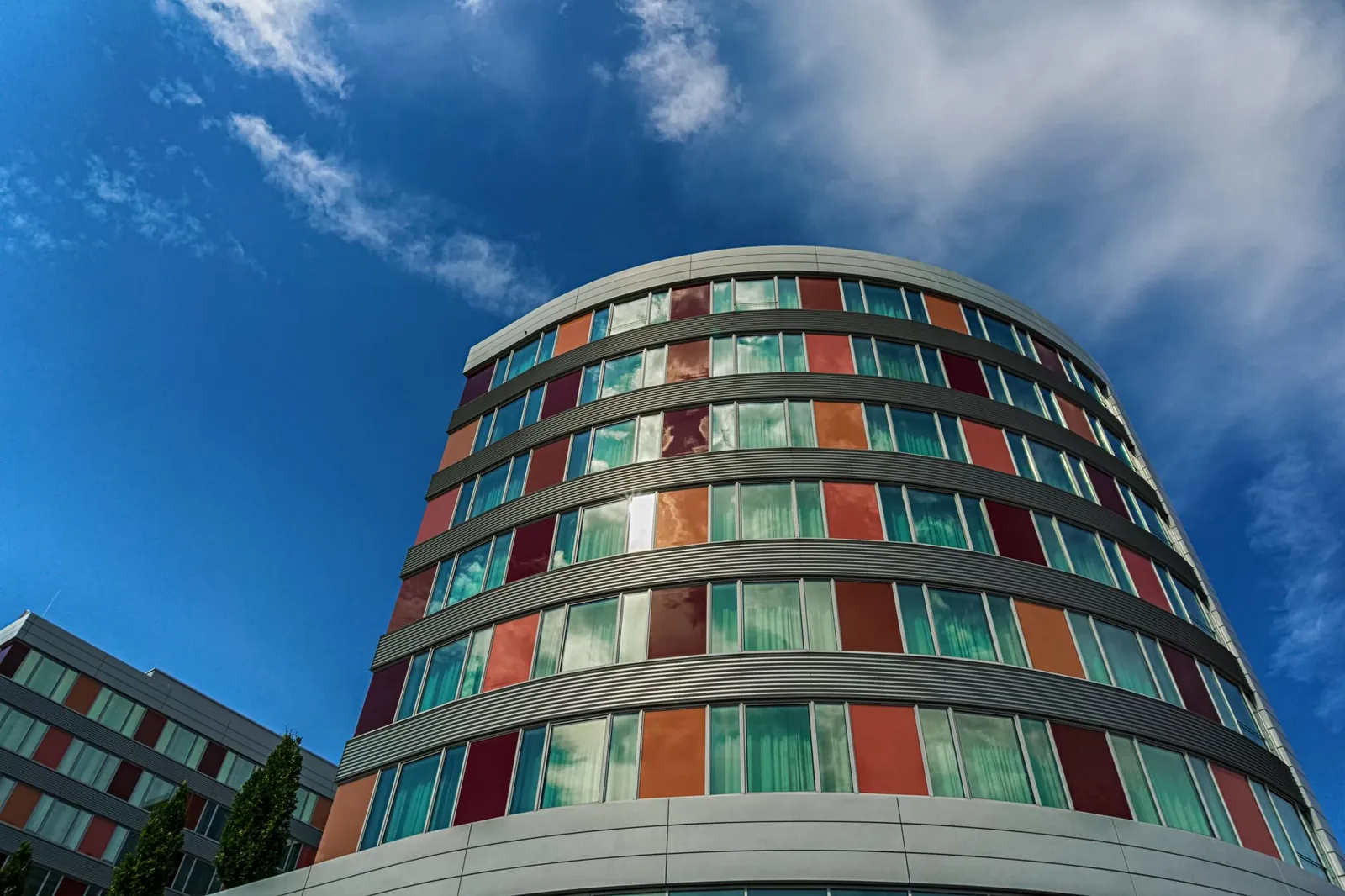 A modern curved building with colorful panels against a blue sky, showcasing urban architecture. Stock photo illustrating Krishna Institute of Medical Sciences' fund raise story.