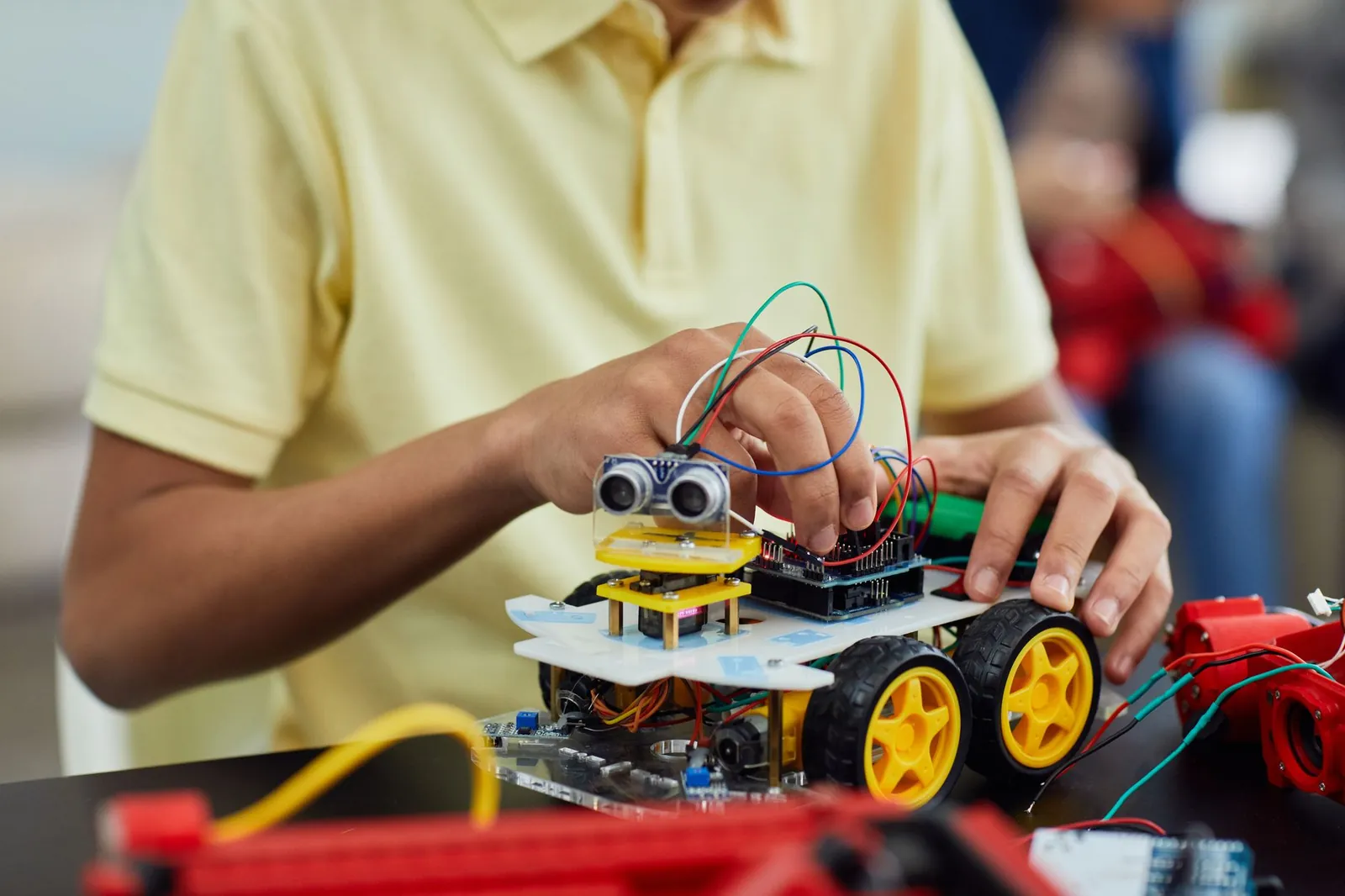 A child engaging in a STEM activity by assembling a robotic toy car featuring electronics and wiring. Stock photo illustrating Maruti Suzuki India's production started story.